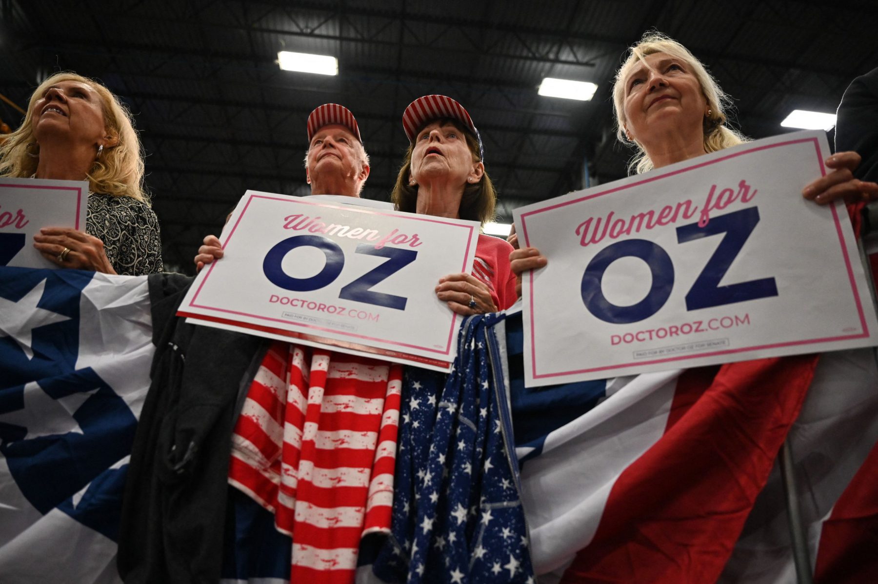 Supporters hold signs reading "Women for Oz" as they listen as US candidate for senate Mehmet Oz speaks during a rally on the outskirts of Bethlehem, Pennsylvania on November 6, 2022. (Photo by Ed JONES / AFP) (Photo by ED JONES/AFP via Getty Images)