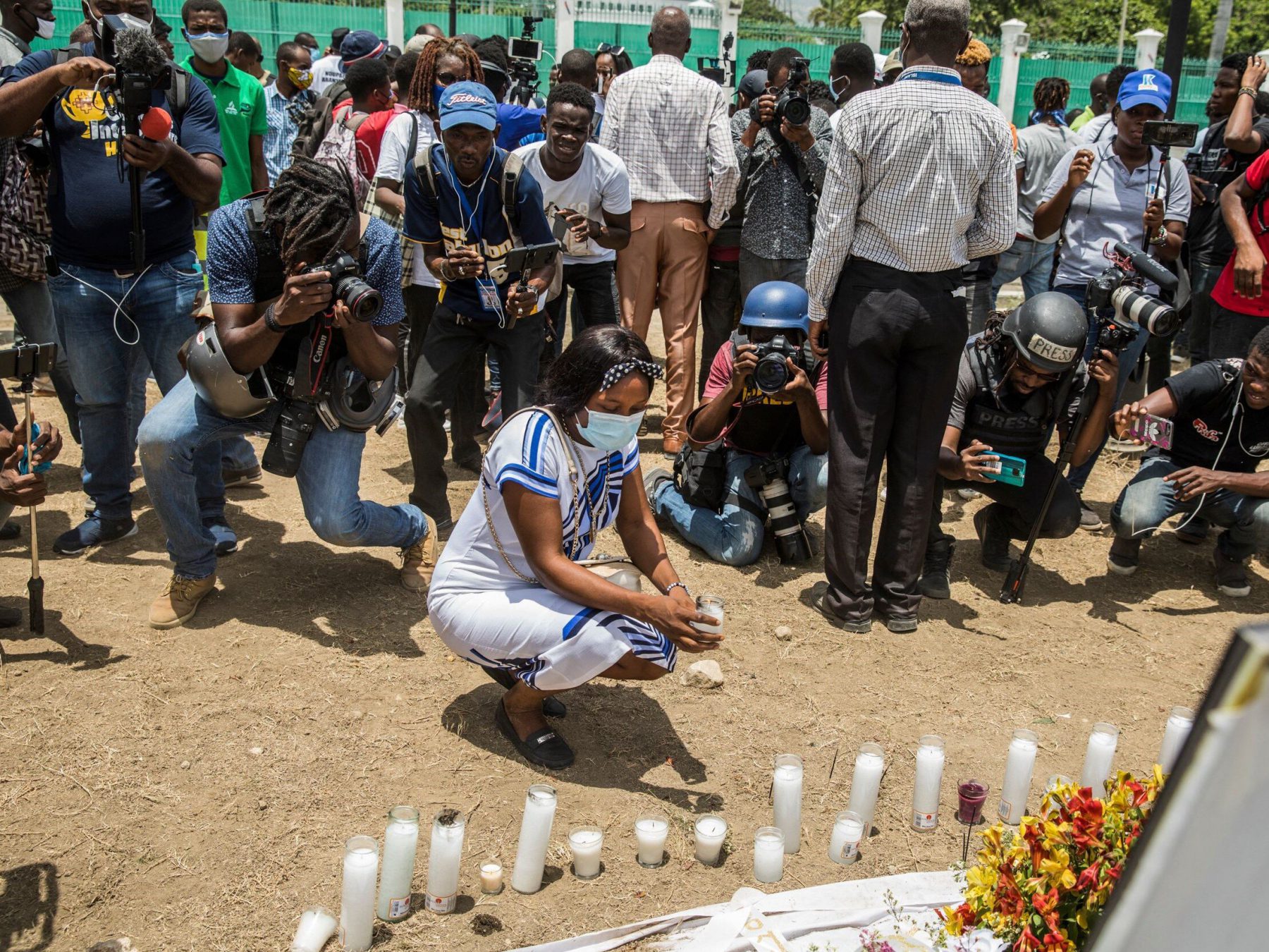 A woman places a candle at a makeshift memorial outside of the Presidential Palace in Port-au-Prince, Haiti.