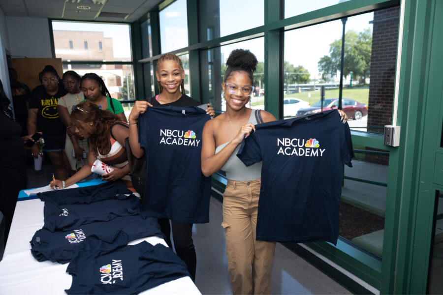 University students smiling and holding NBCU Academy t-shirts