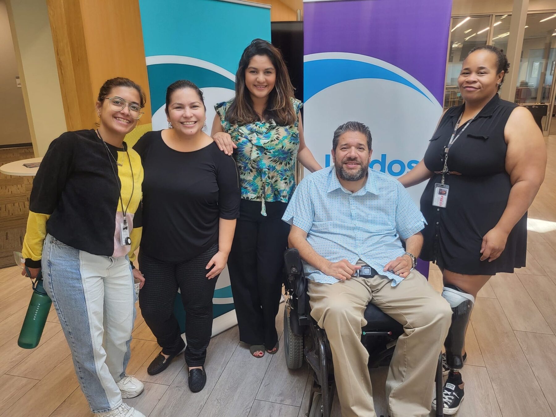 Four women stand next to a man sitting in a wheelchair.